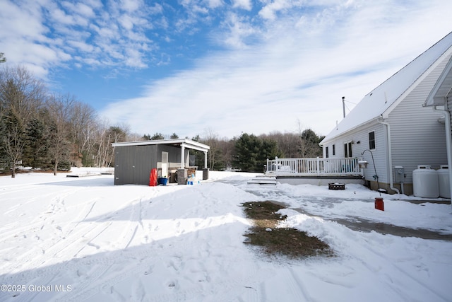 yard layered in snow with a storage unit and a deck