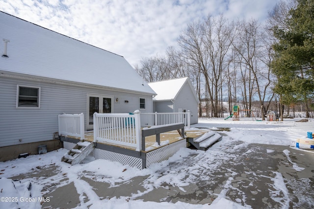 yard layered in snow with a playground and a deck