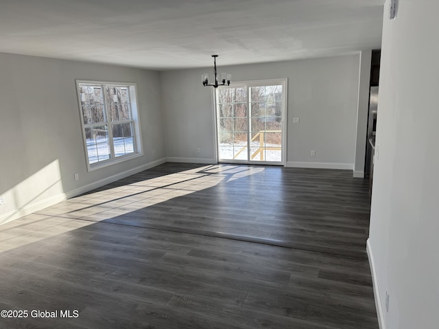 unfurnished dining area featuring a notable chandelier, dark wood-type flooring, and a wealth of natural light