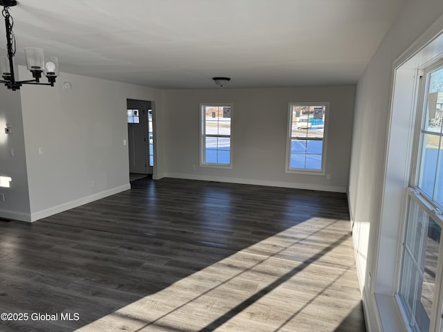 unfurnished room featuring dark wood-type flooring and an inviting chandelier