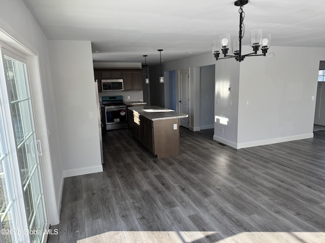 kitchen featuring a kitchen island, appliances with stainless steel finishes, dark wood-type flooring, dark brown cabinets, and an inviting chandelier