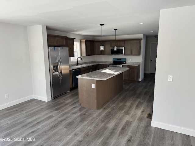 kitchen featuring sink, appliances with stainless steel finishes, dark hardwood / wood-style floors, a kitchen island, and decorative light fixtures