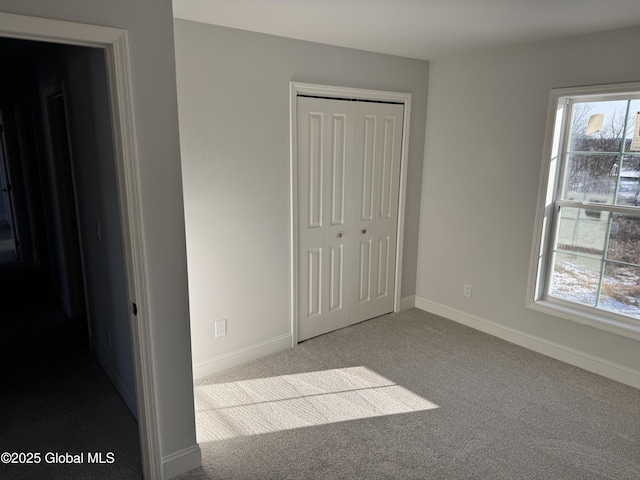 unfurnished bedroom with multiple windows, light carpet, and a closet