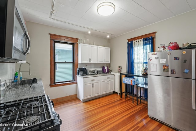 kitchen featuring white cabinetry, light hardwood / wood-style flooring, stainless steel appliances, and rail lighting