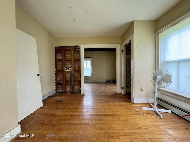 hall with baseboard heating and light hardwood / wood-style floors