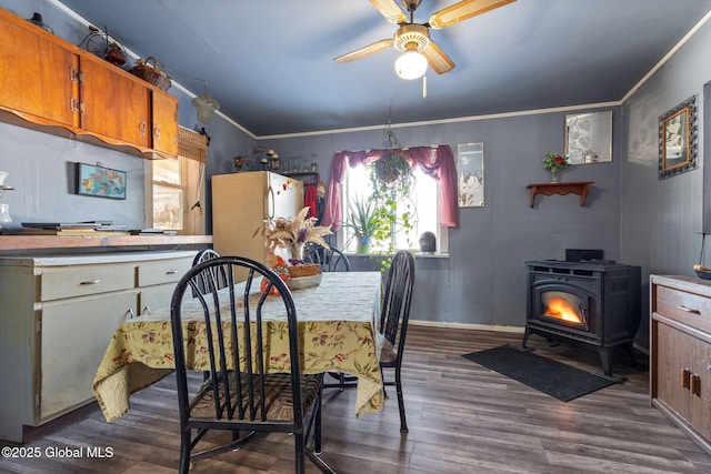 dining area featuring crown molding, dark hardwood / wood-style floors, ceiling fan, and a wood stove