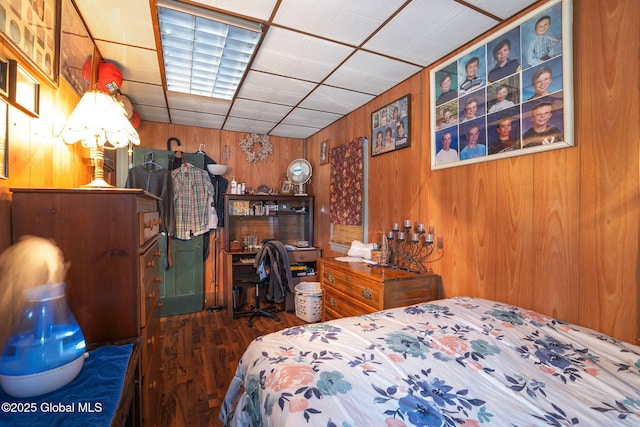 bedroom featuring a paneled ceiling and wooden walls