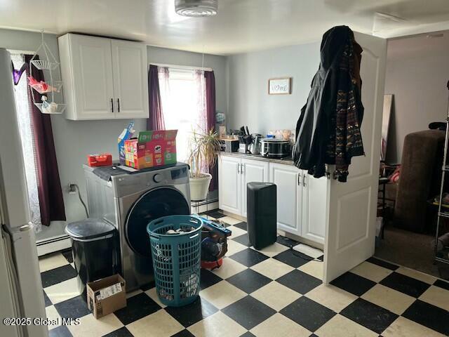 washroom featuring a baseboard heating unit, washer / clothes dryer, cabinet space, and light floors