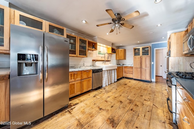 kitchen featuring stainless steel appliances, decorative backsplash, sink, ceiling fan, and light hardwood / wood-style flooring