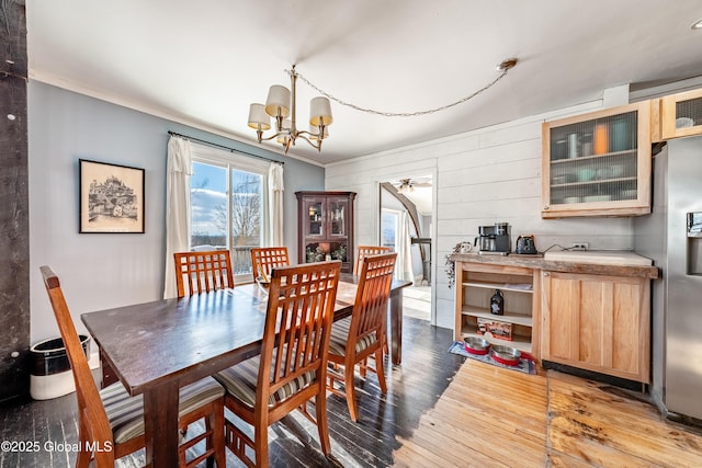 dining space featuring a chandelier, wood walls, ornamental molding, and light hardwood / wood-style floors