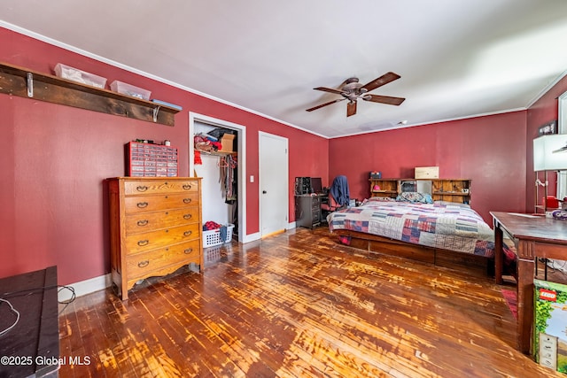 bedroom with hardwood / wood-style floors, crown molding, a walk in closet, a closet, and ceiling fan