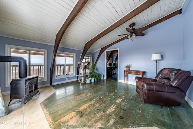 living room with ceiling fan, vaulted ceiling with beams, a wood stove, and wood ceiling