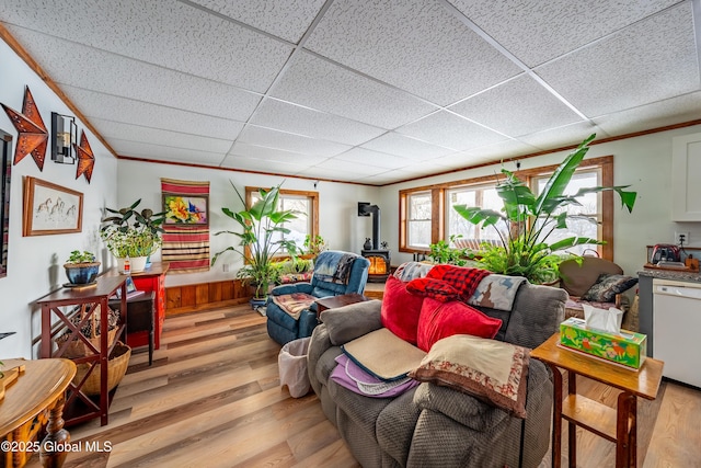 living room featuring light hardwood / wood-style floors, a wood stove, a paneled ceiling, and crown molding