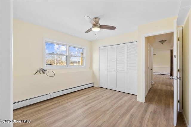 unfurnished bedroom featuring a baseboard radiator, light wood-type flooring, a closet, and ceiling fan