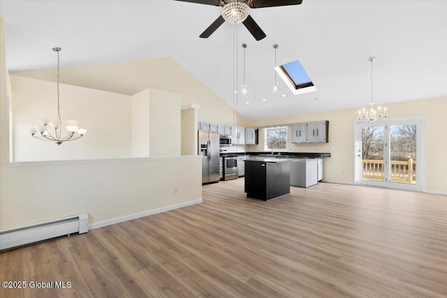 kitchen with decorative light fixtures, appliances with stainless steel finishes, a center island, and light wood-type flooring