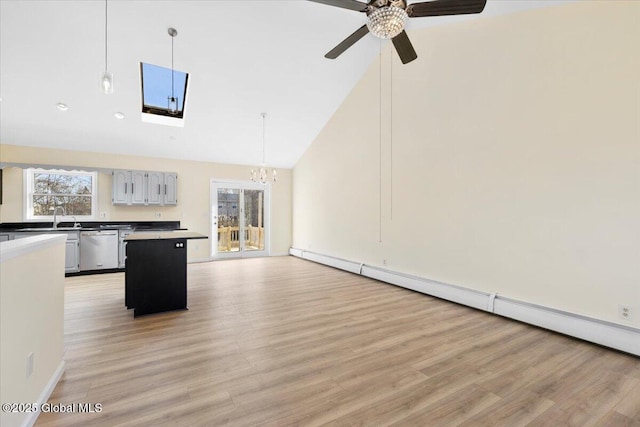 unfurnished living room with baseboard heating, sink, high vaulted ceiling, light hardwood / wood-style flooring, and ceiling fan with notable chandelier