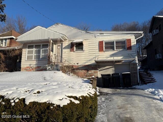 snow covered rear of property featuring a garage