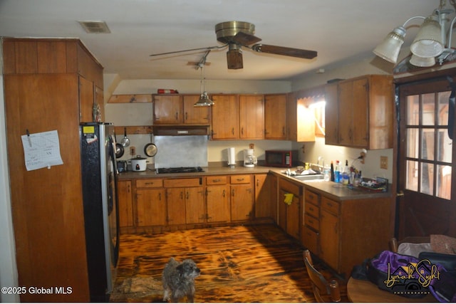kitchen featuring a ceiling fan, visible vents, freestanding refrigerator, and brown cabinetry
