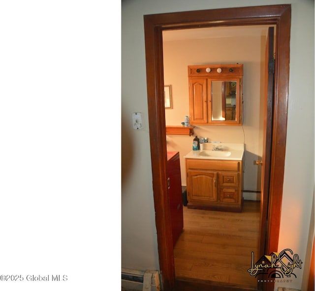 bathroom featuring a baseboard heating unit, vanity, and wood finished floors