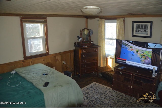 bedroom featuring wainscoting, wood finished floors, and wood walls