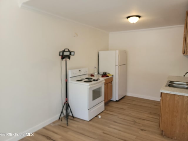 kitchen with ornamental molding, sink, white appliances, and light wood-type flooring