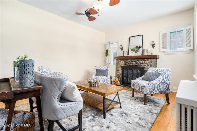 sitting room featuring ceiling fan, wood-type flooring, and a fireplace