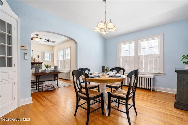 dining room featuring lofted ceiling, radiator heating unit, and light wood-type flooring