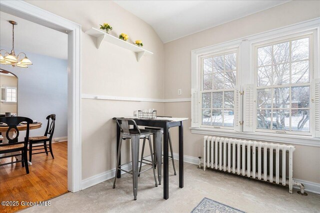 dining room featuring lofted ceiling, radiator, and a notable chandelier