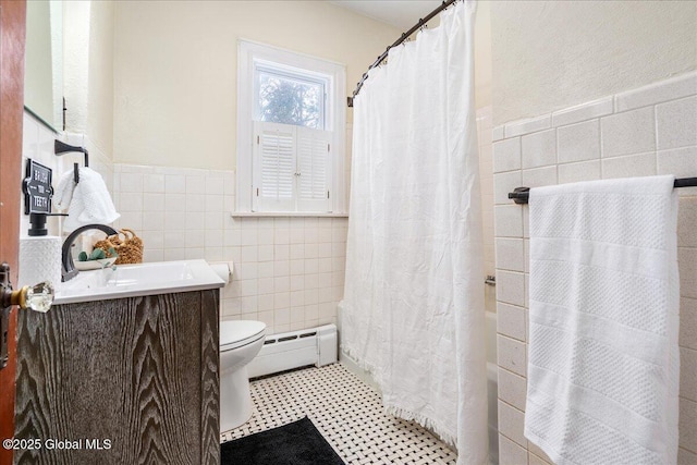 bathroom with a baseboard radiator, vanity, toilet, and tile walls