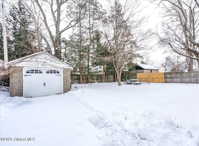 yard layered in snow featuring a garage and an outdoor structure