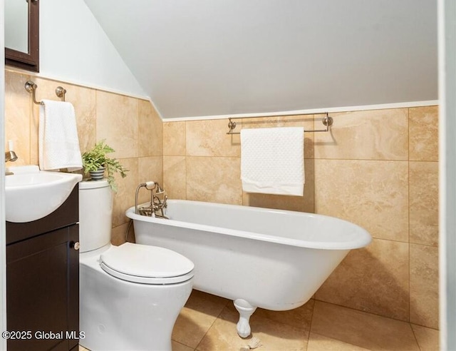 bathroom with tile walls, a bathing tub, vanity, vaulted ceiling, and toilet