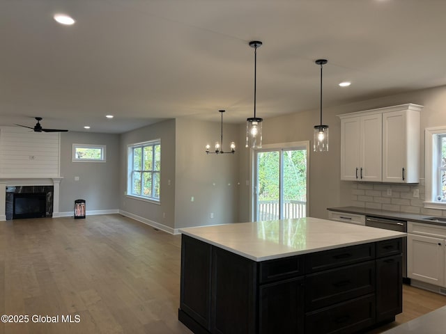 kitchen featuring tasteful backsplash, white cabinetry, a center island, a premium fireplace, and light wood-type flooring