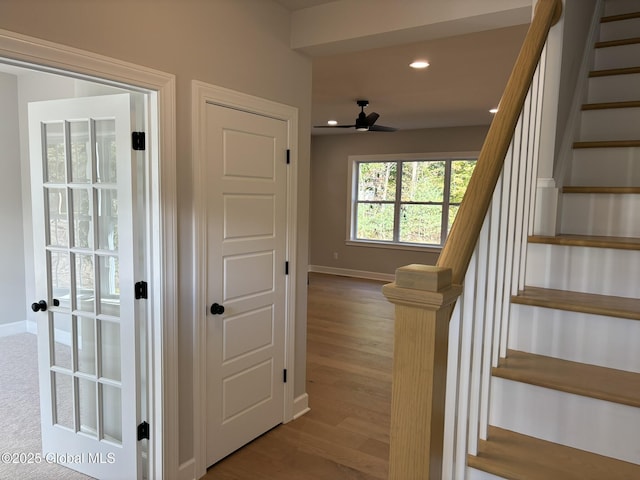 staircase with ceiling fan and wood-type flooring