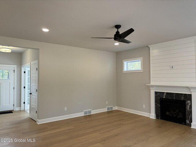 unfurnished living room with wood-type flooring, ceiling fan, and a fireplace