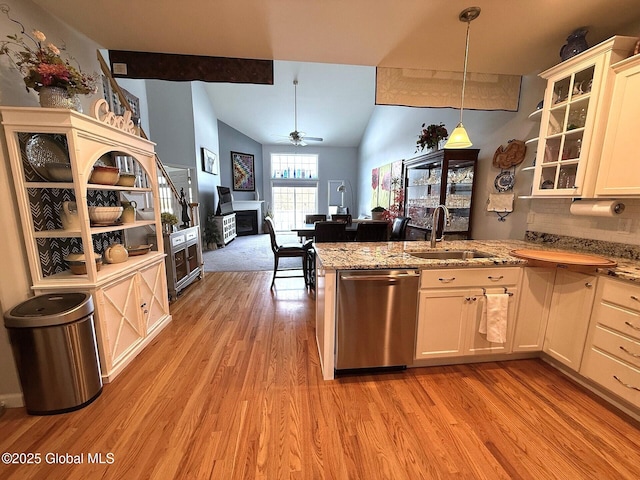 kitchen featuring dishwasher, white cabinetry, sink, decorative light fixtures, and vaulted ceiling