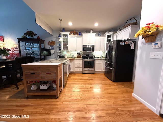 kitchen with white cabinetry, sink, pendant lighting, and stainless steel appliances