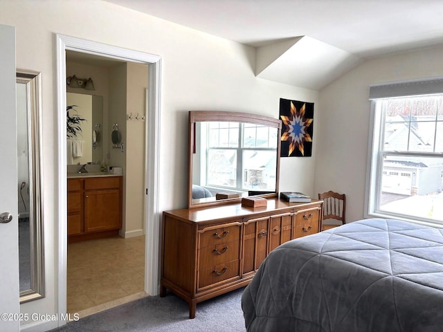 bedroom with sink, light carpet, ensuite bath, and lofted ceiling