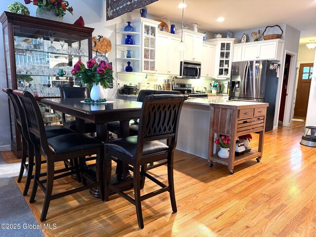 kitchen with white cabinets, tasteful backsplash, light hardwood / wood-style floors, and appliances with stainless steel finishes