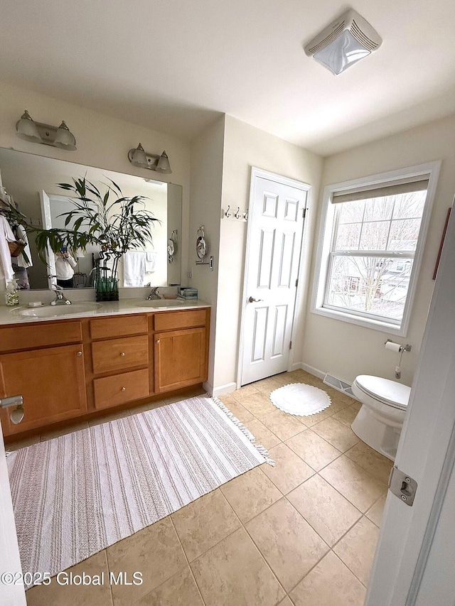 bathroom with toilet, vanity, and tile patterned flooring