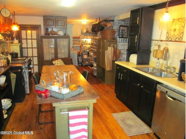 kitchen with stainless steel appliances, decorative light fixtures, sink, and light wood-type flooring