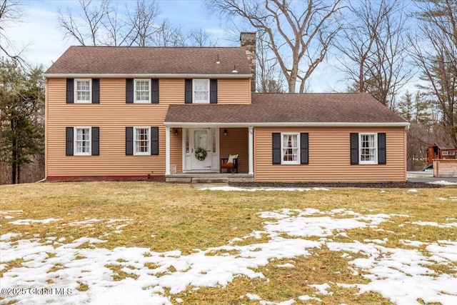 view of front facade featuring a shingled roof, a chimney, and a front yard