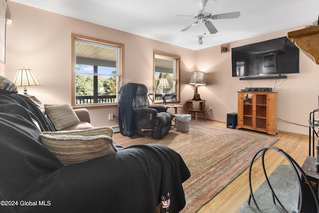 living room featuring ceiling fan, light hardwood / wood-style floors, and a baseboard heating unit