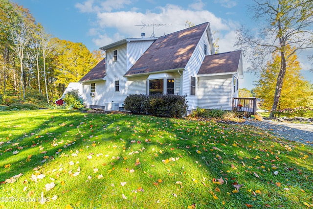 view of side of home with a deck, a lawn, and central air condition unit