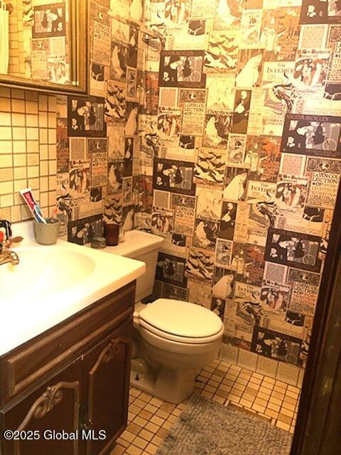 bathroom featuring vanity, toilet, tile patterned flooring, and backsplash