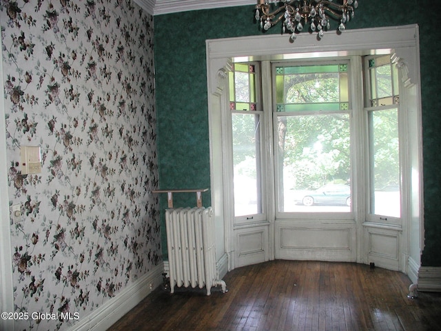 unfurnished room with dark hardwood / wood-style flooring, radiator, and a notable chandelier