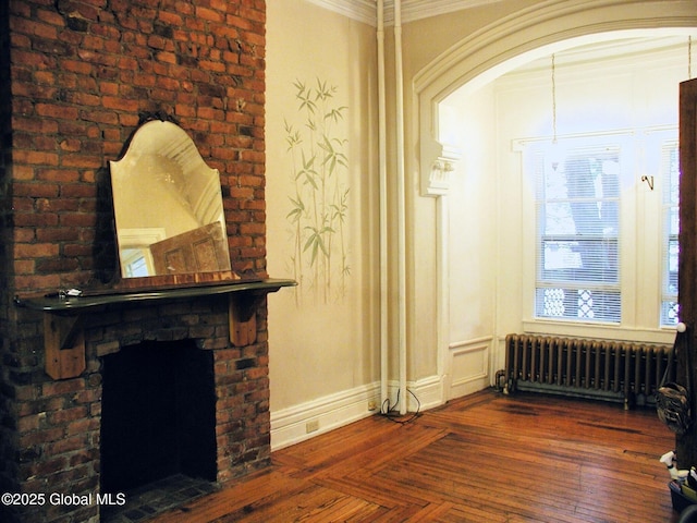 living room with a brick fireplace, crown molding, and radiator heating unit