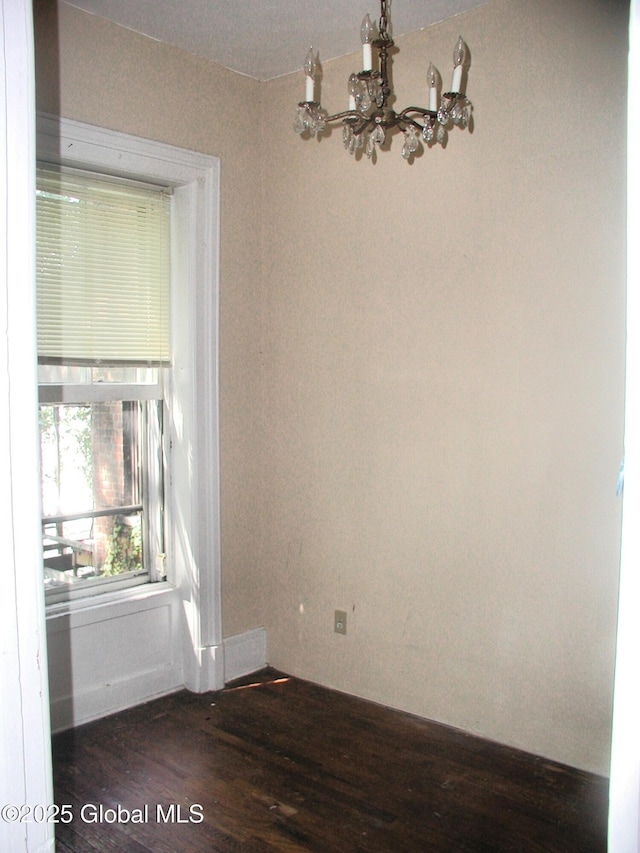 spare room featuring dark hardwood / wood-style floors and an inviting chandelier