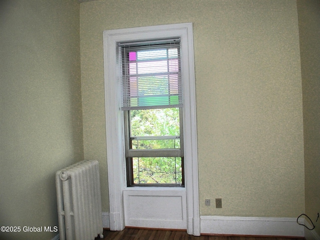 doorway to outside with radiator heating unit and dark hardwood / wood-style flooring