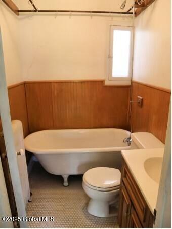 bathroom with tile patterned flooring, vanity, a bath, and wooden walls