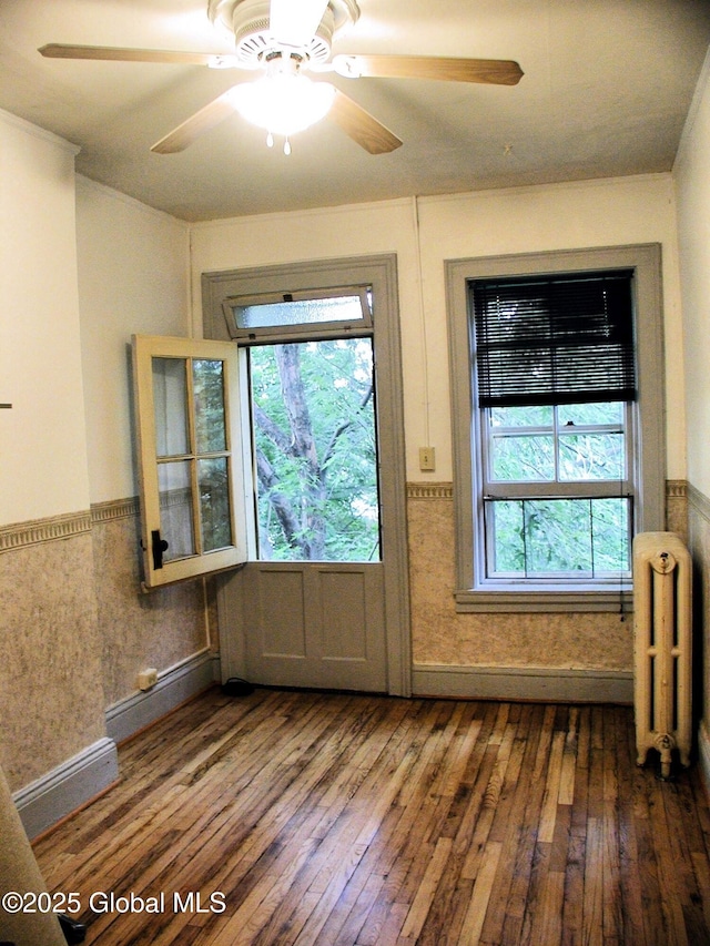 entryway with dark wood-type flooring, ceiling fan, and radiator heating unit